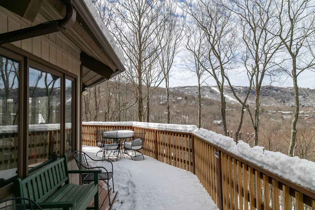This image shows an inviting deck with comfortable seating, surrounded by snow-covered ground and offering a breathtaking view of the mountains. The deck is positioned to capture the wide expanse of the landscape, suggesting an ideal spot for sunrise coffee, sunset relaxation, or simply enjoying the outdoors.